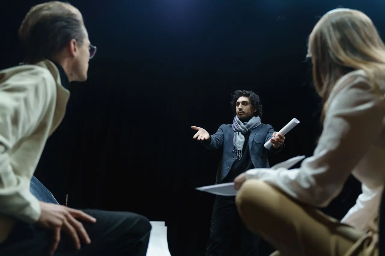 Director de teatro que guía a dos actores en un ensayo